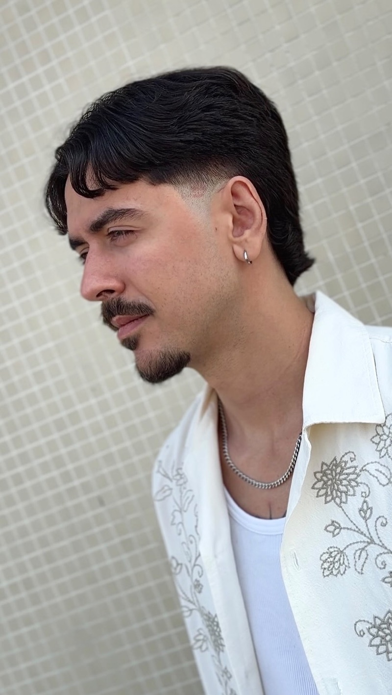 Cliente com corte moderno de risco ao meio e barba desenhada