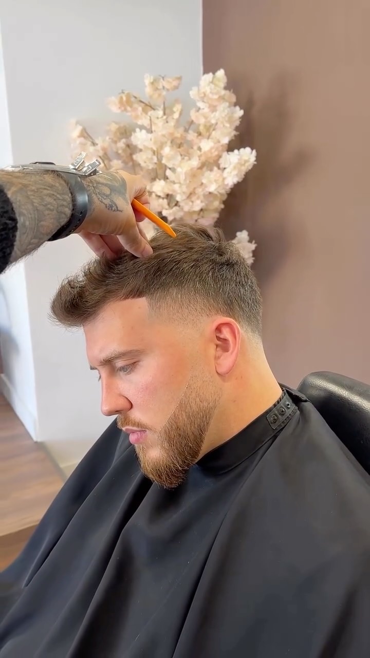 Barbeiro a pentear o cabelo de um cliente durante o corte