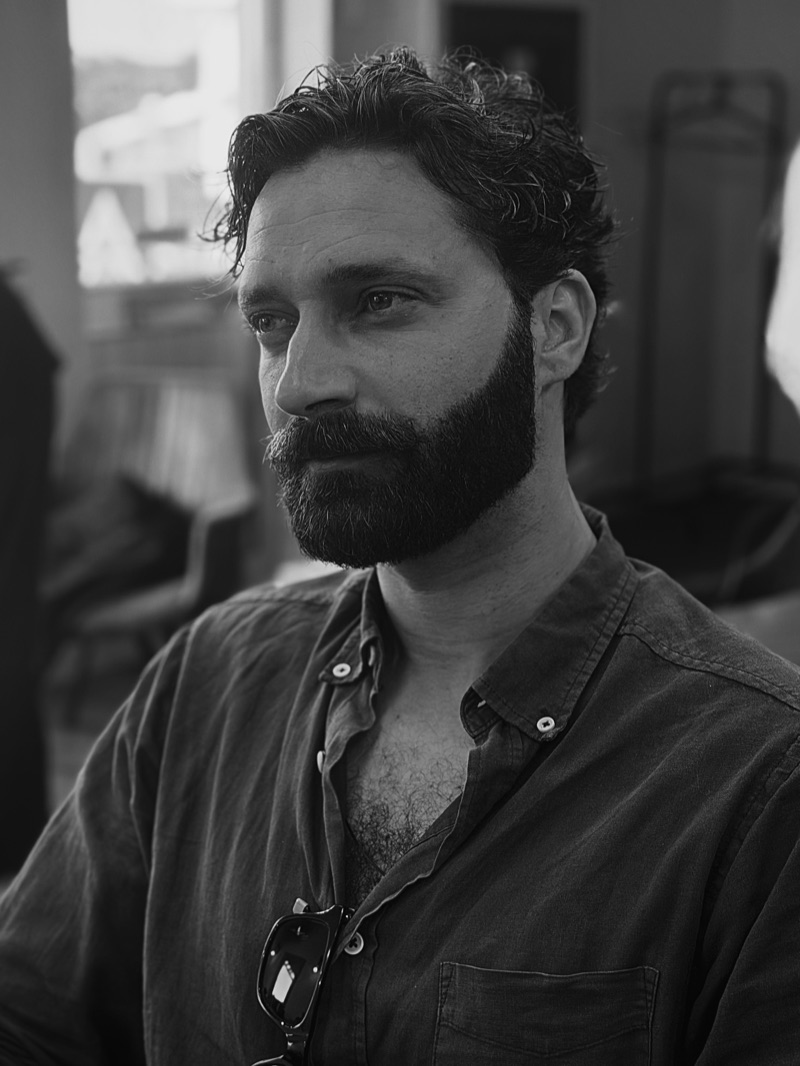 Retrato a preto e branco de um cliente com barba cheia aparada à lâmina